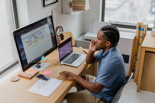 A man concentrates on a mind map displayed on a computer monitor in a modern office.