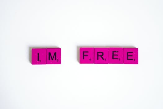 Pink Scrabble tiles arranged to spell 'I'm free' on a white background, conveying freedom.
